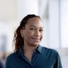 Black woman with braids wearing a green blouse and smiling at the camera.